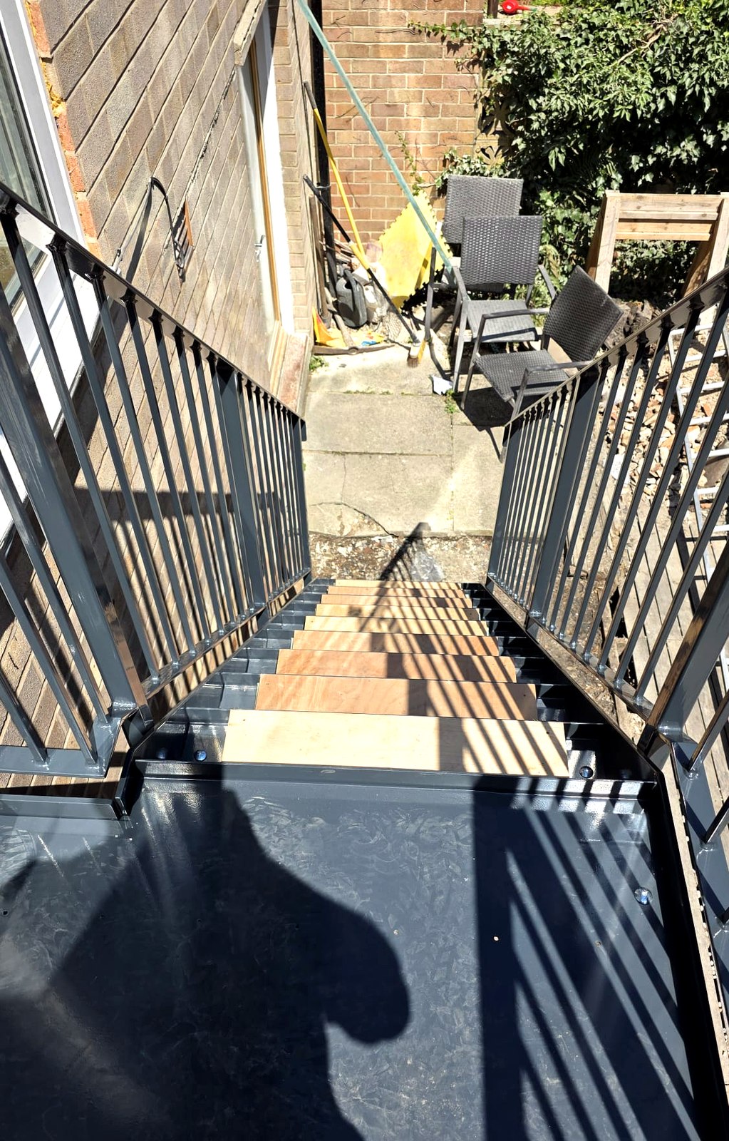 Galvanised and powder-coated steel external staircase between brick walls, Sheffield